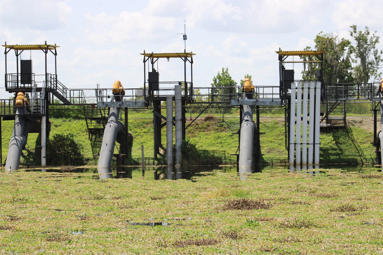 Water lock system with pipes and steel structures in a grassy field.